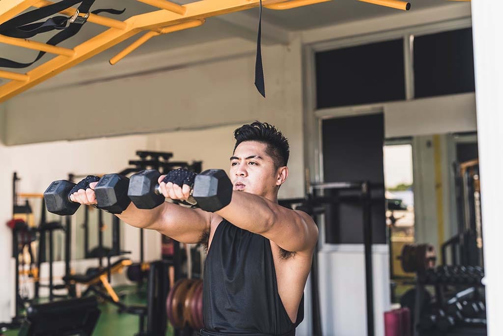 A man does a dumbbell front raise to target the anterior (front) deltoid muscles