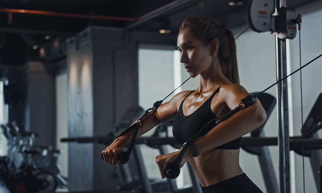 Woman working with cable machine at gym 