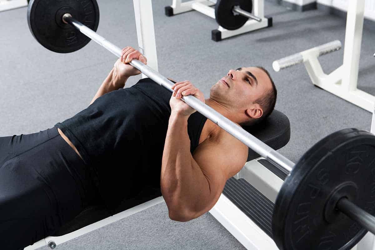 young bodybuilder training in the gym: triceps - close grip barbell bench press