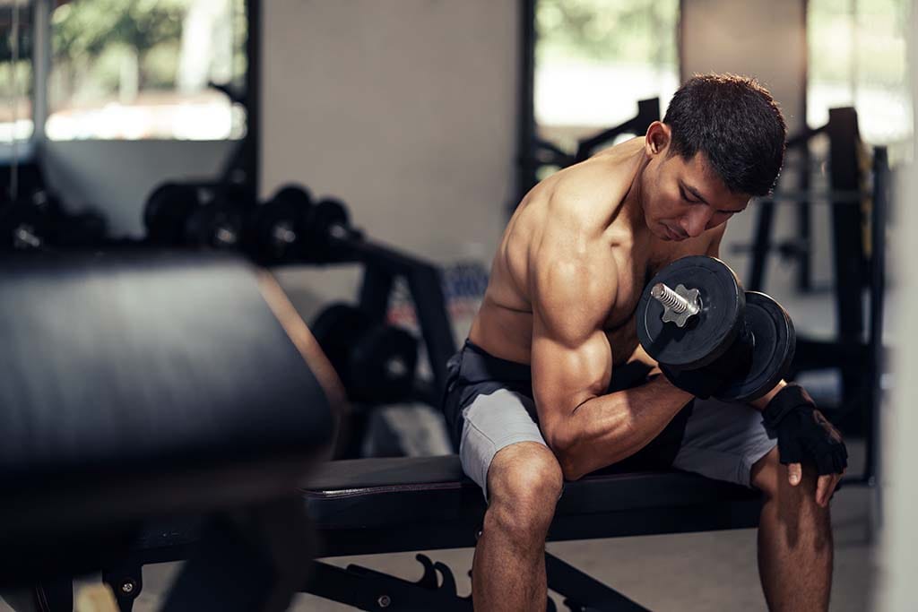 A fit man performs pinwheel curls for stronger arms.