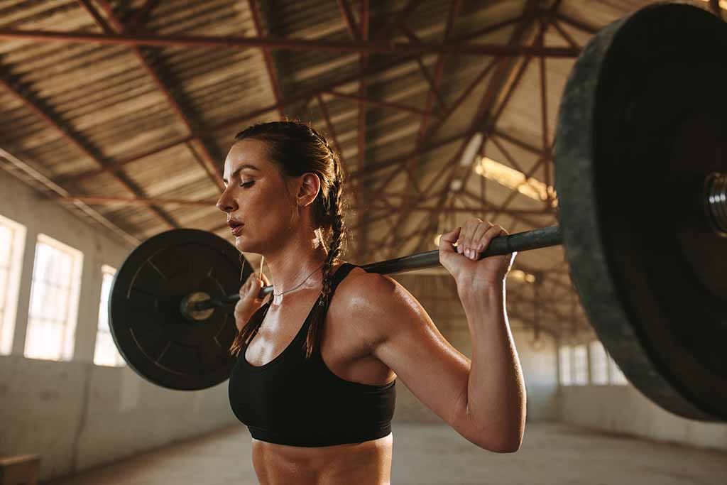 A woman holds a weighted barbell for squats.