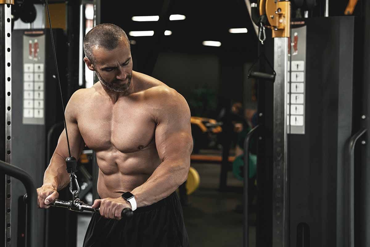 A muscular man does tricep pushdowns for stronger arms