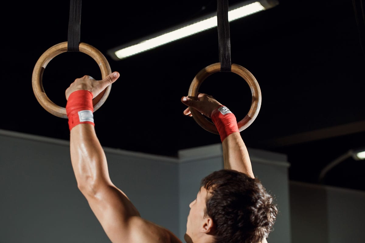 A man does pull-ups on hanging rings.