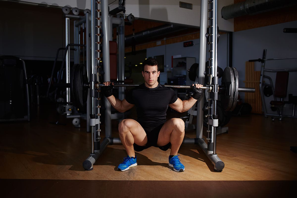 a man doing Asian squat with weight at gym