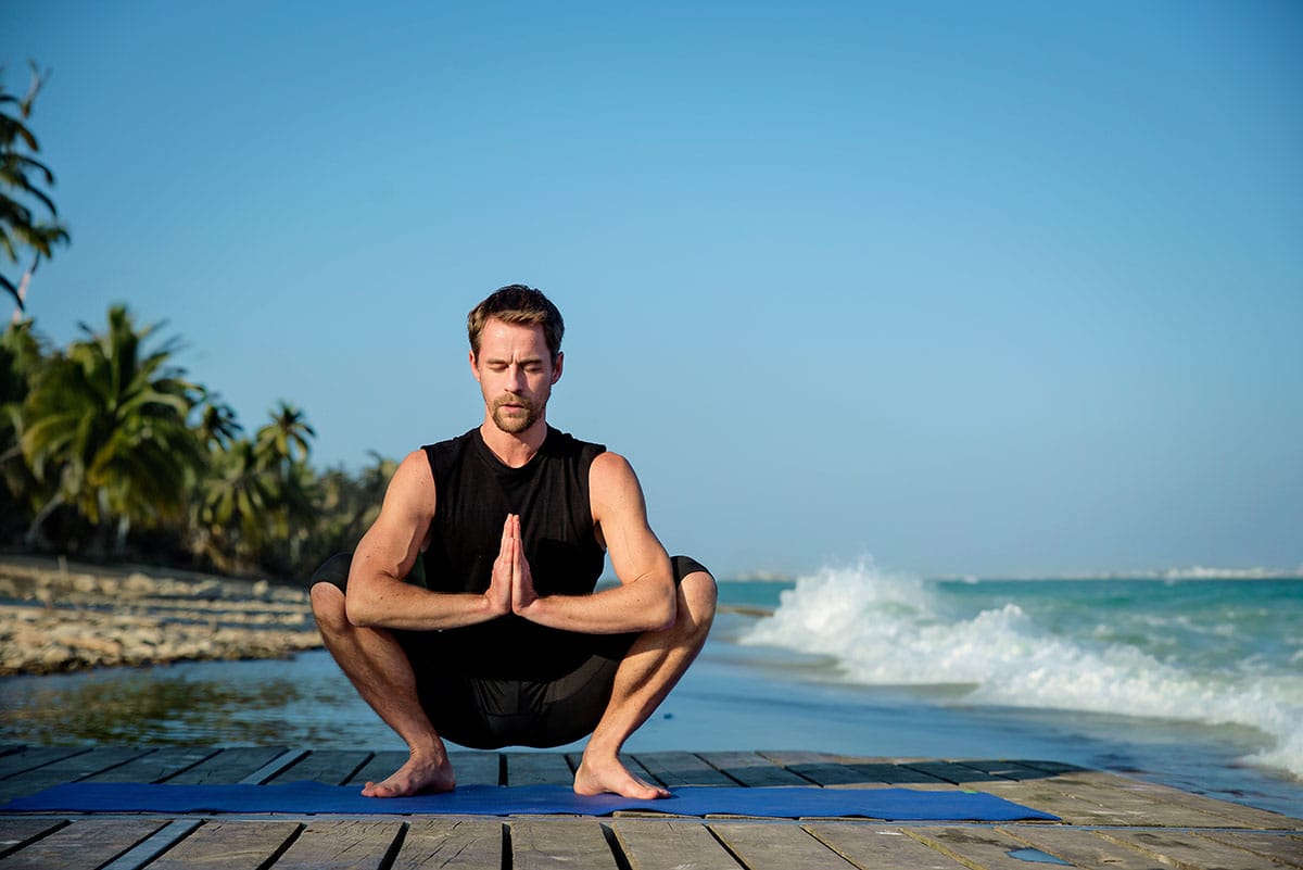 a man doing yoga at Asian squat position