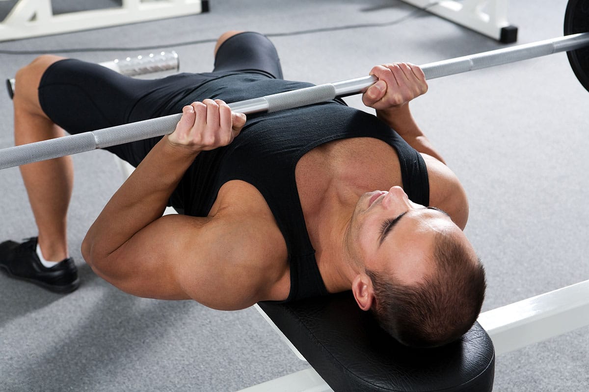 Young man training a bench press with suicide grip