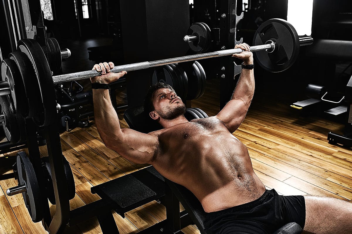 A man bench presses without thumbs wrapped around the bar, a riskier variation.