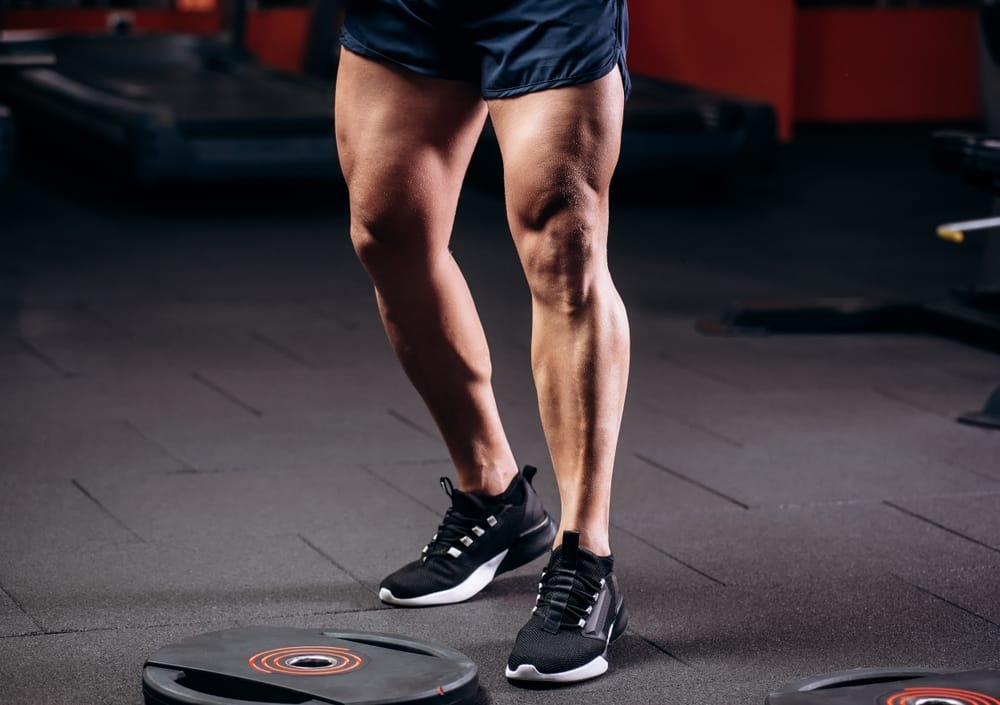 Healthy Young Man Standing Strong in the Gym and Flexing Legs Close Up