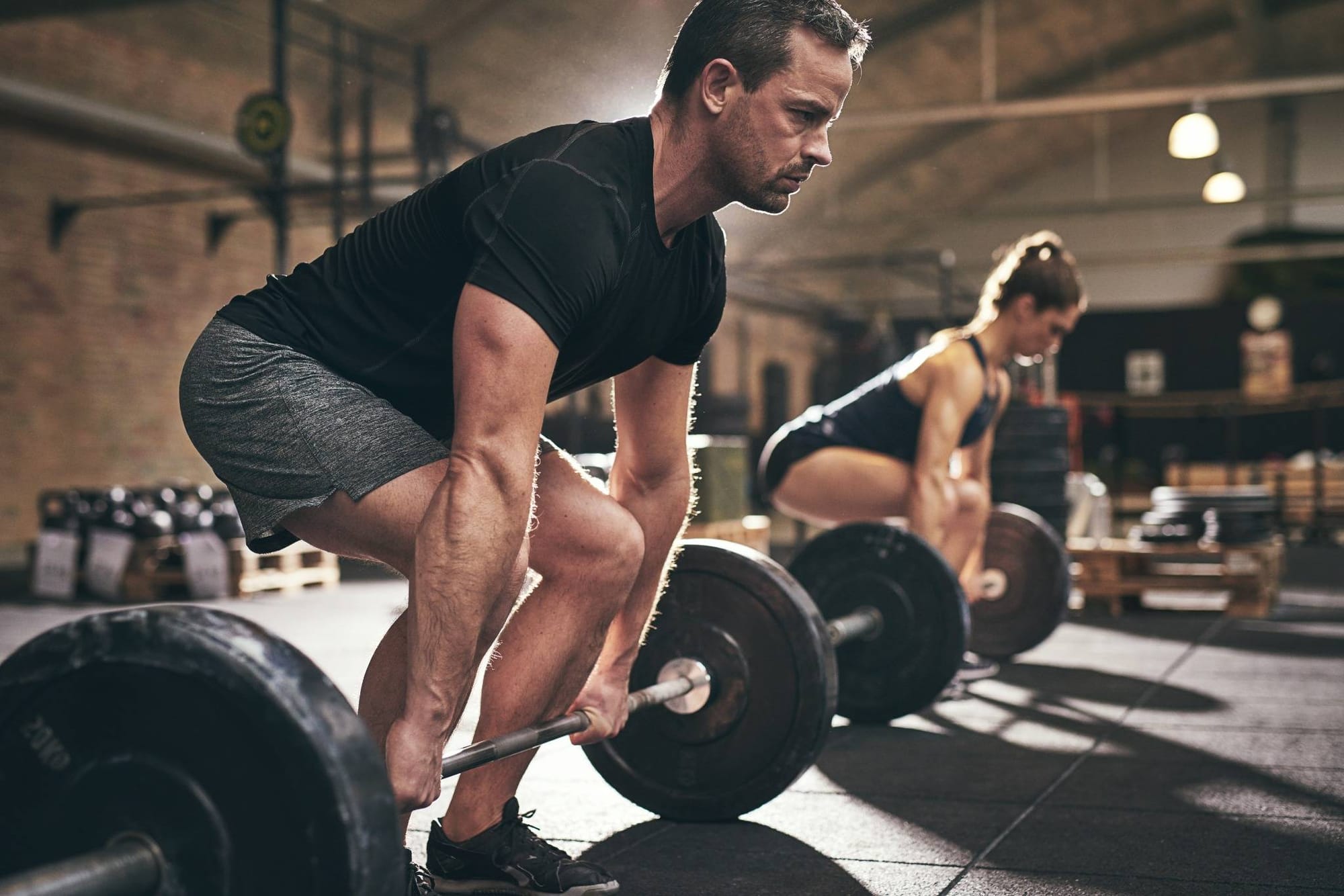 Man and woman performing a deadlift exercise in a gym