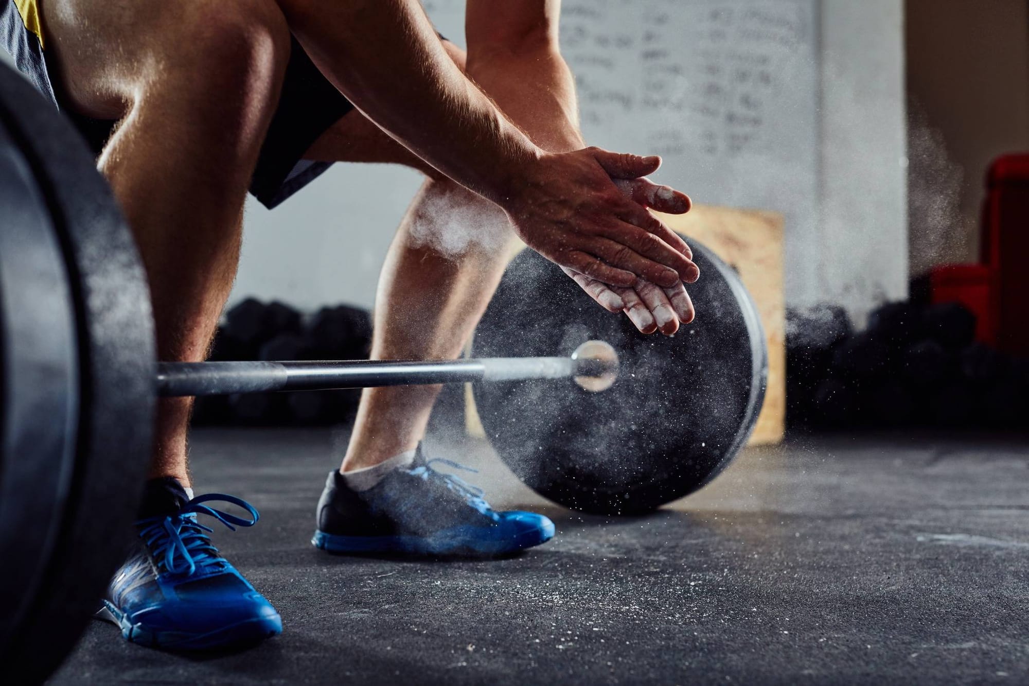 Close-up of a weightlifter applying chalk to hands before performing a deadlift