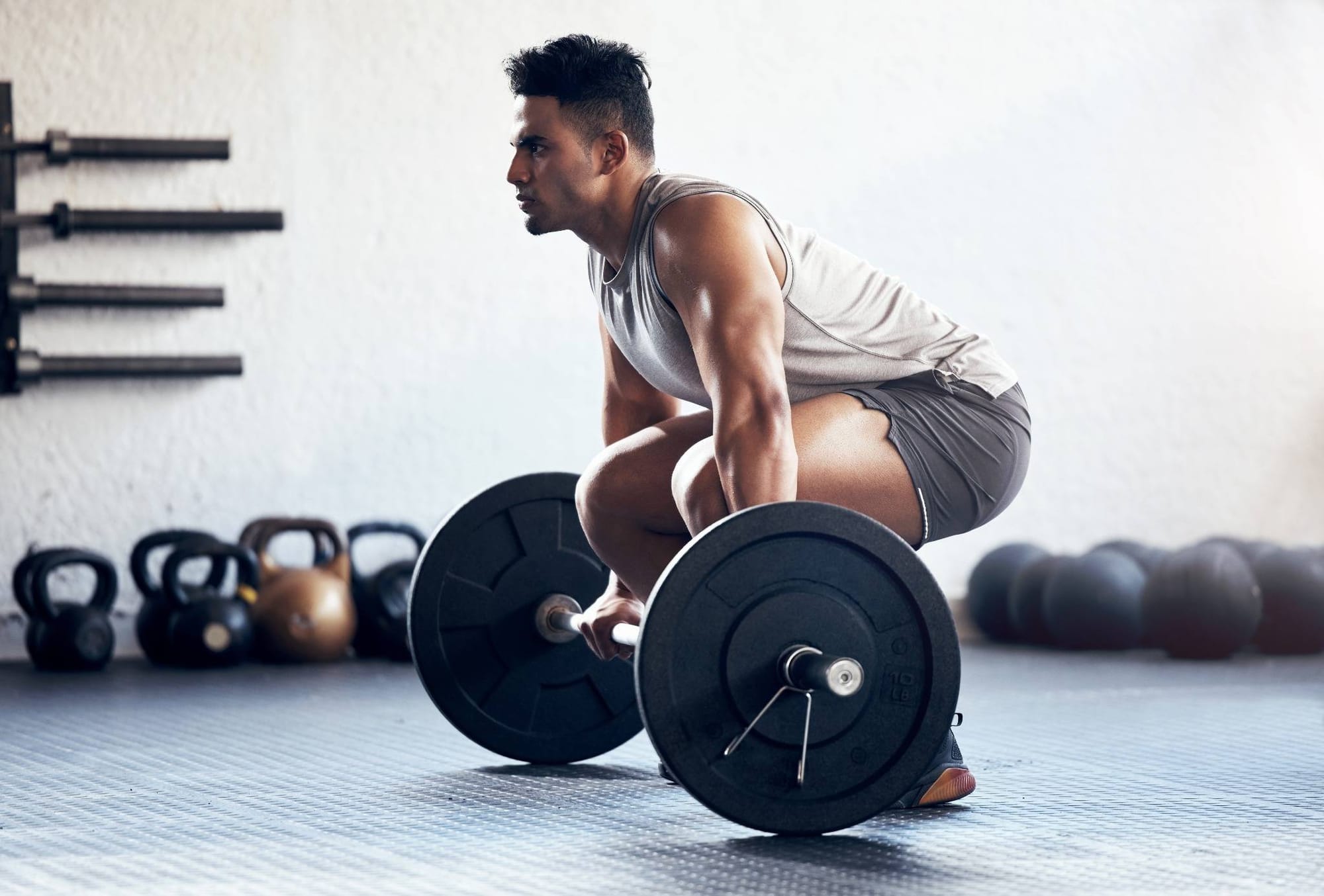 Focus on keeping your chest up and spine neutral.Athletes performing deadlifts in a gym, focusing on proper form and strength training.