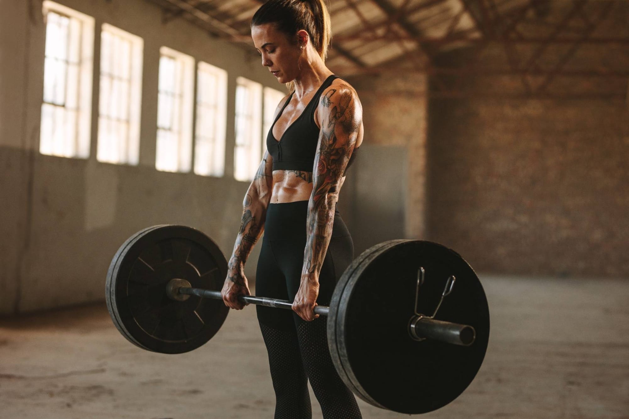 Strong female athlete demonstrating the lockout stage of a deadlift.