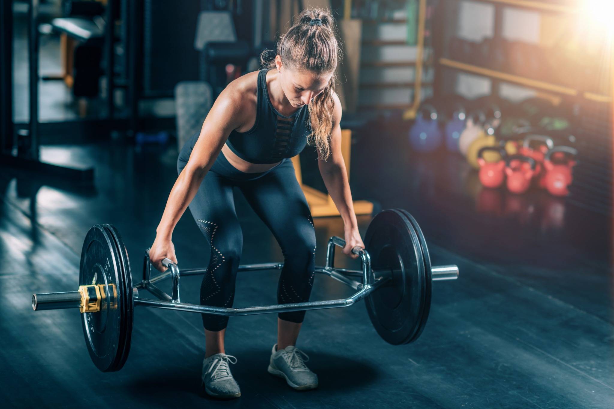 Fit woman performing a trap bar deadlift in the gym