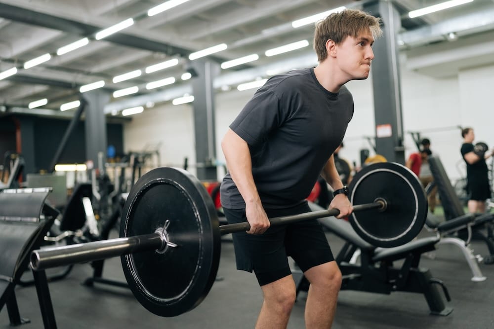 person lifting a barbell doing a deadlift at the gym