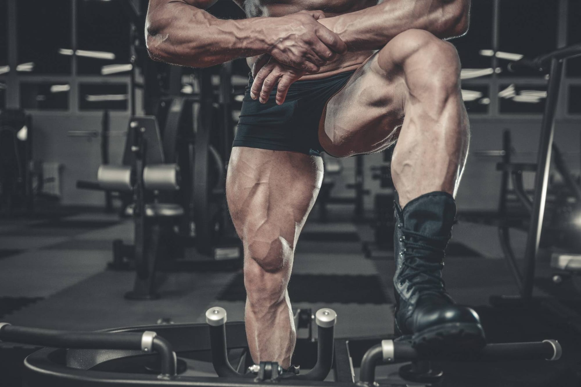 Close-up of a muscular man's legs in the gym, highlighting vascularity and lower body development.