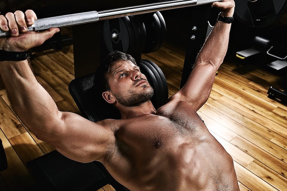 muscular man lifting a barbell bench press