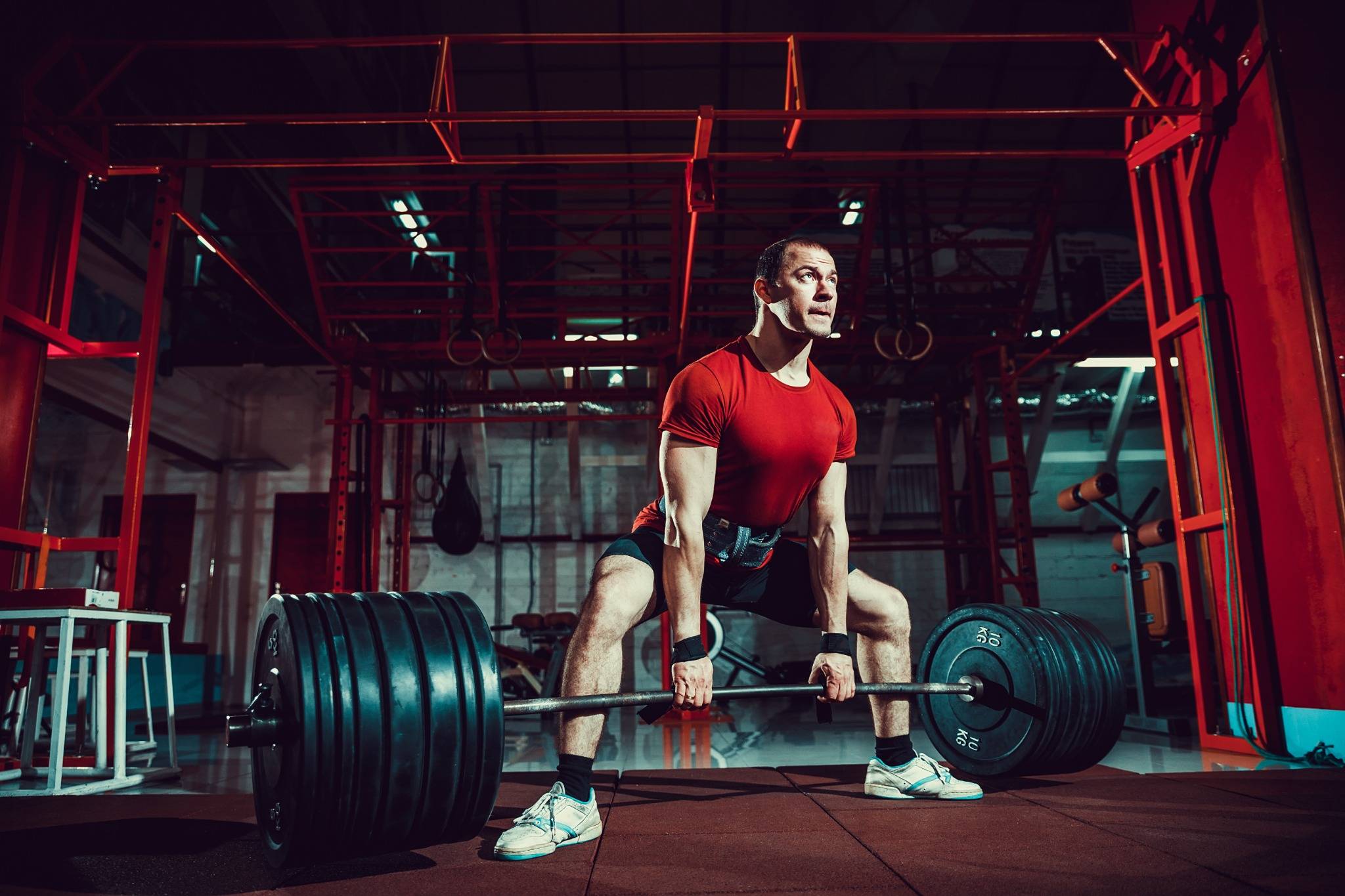 Athlete performing a sumo deadlift in a gym with a heavily loaded barbell,