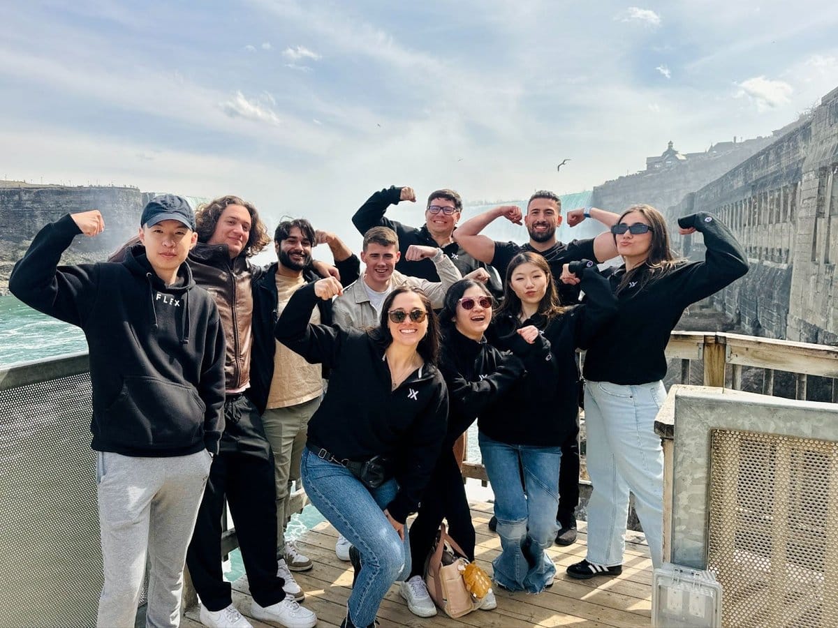 Flex AI team celebrating their AI form feedback innovation near a scenic waterfall